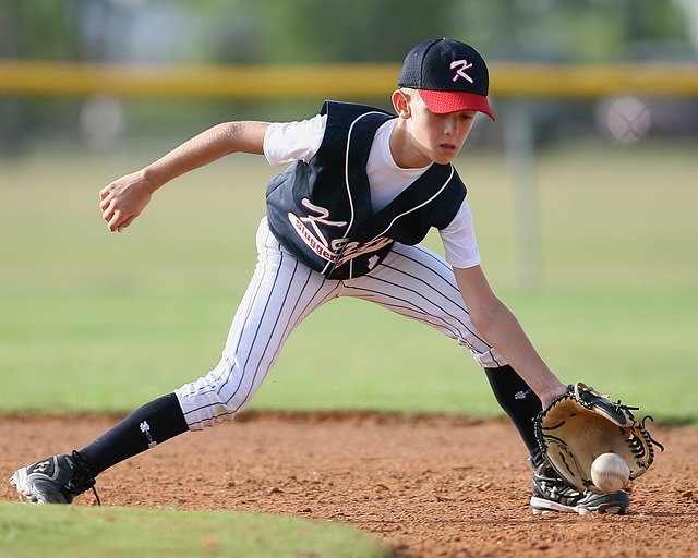 a youth player fielding a baseball cleanly to not allow an earned run